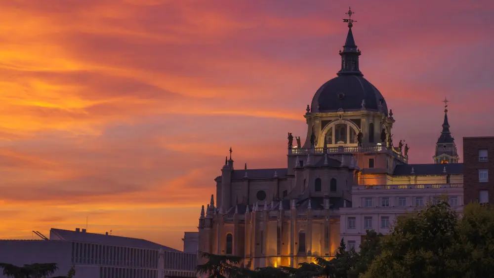 Cúpula de la Catedral de la Almudena de madrid en un atardecer con rojos y anaranjados en el cielo